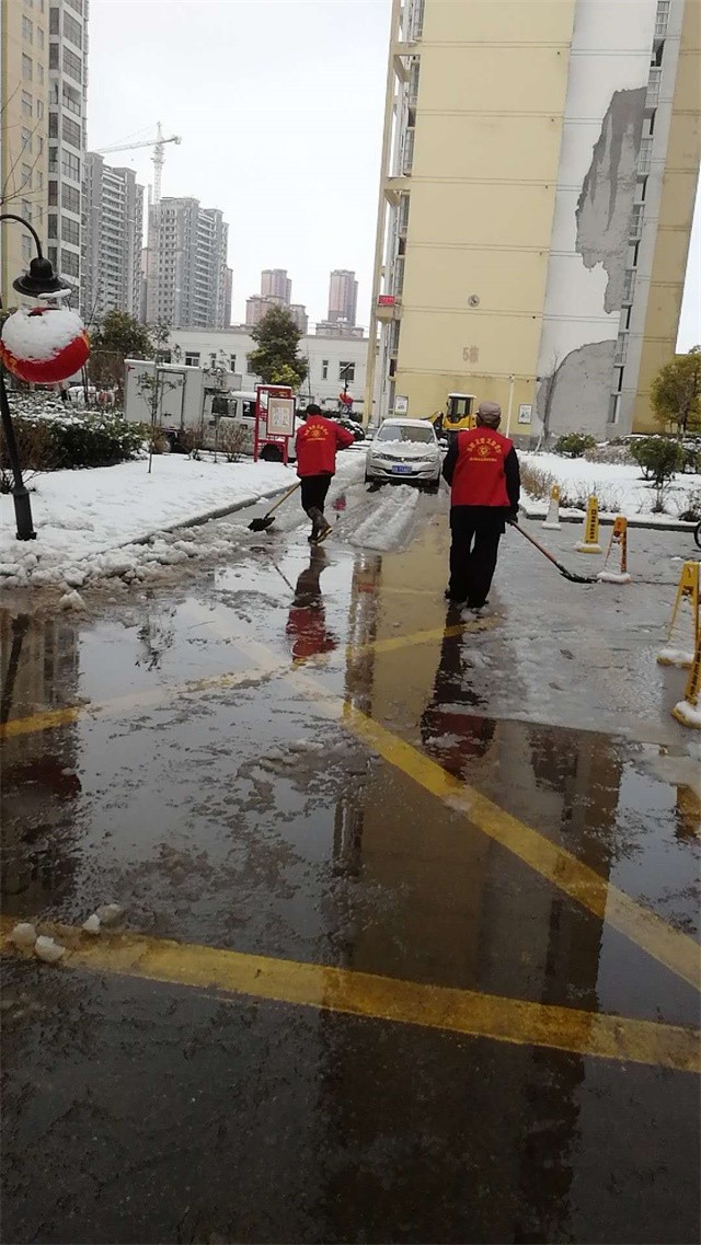 志愿者幫忙清掃小區(qū)路面積雪